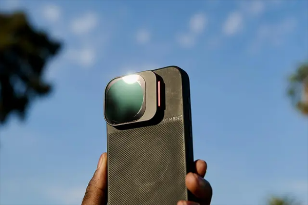 someone holding a phone in a moment case with the vnd filter attached in the air