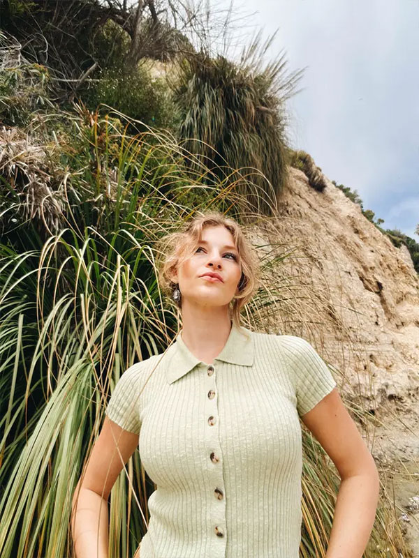 sample portrait of a woman stoof in front of a grassy beach taken using the moment mobile lens
