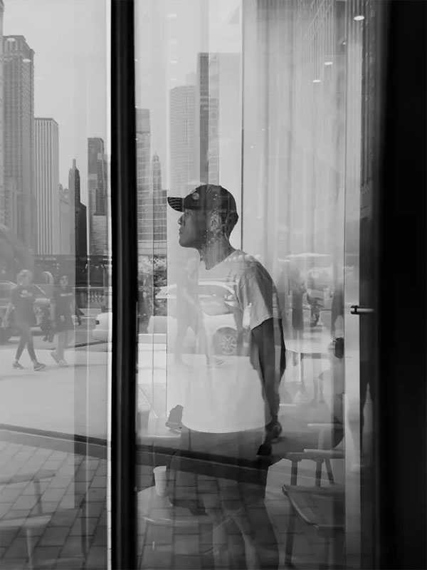 black and white sample photo of a man looking out of a window taken using the moment mobile lens