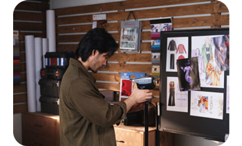 photographer adjusting light controls on Nanlite FC-60B in studio looking at fashion mood board