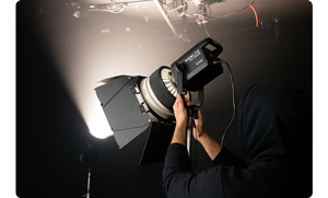 person wearing black hoodie adjusting the bowens mount light modifier attached to Nanlite fs200b