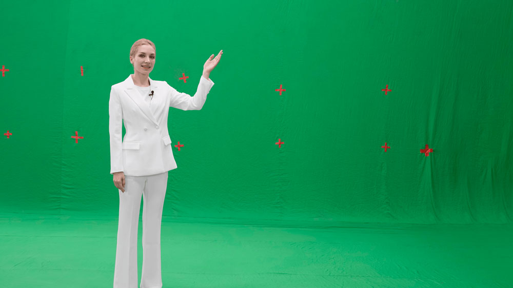 a woman stood in front of a green screen with red markers