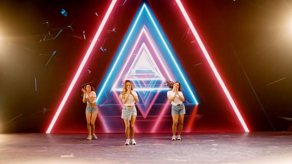 dancers on stage in front of a green screen showing vibrant triangle graphic