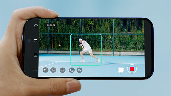 someone holding a smartphone showing the obsbot ptz camera tracking a person playing tennis