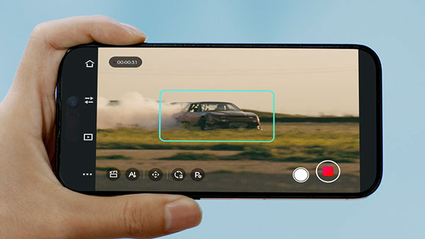 someone holding a smartphone showing the obsbot ptz camera tracking a car driving a long a dirt path
