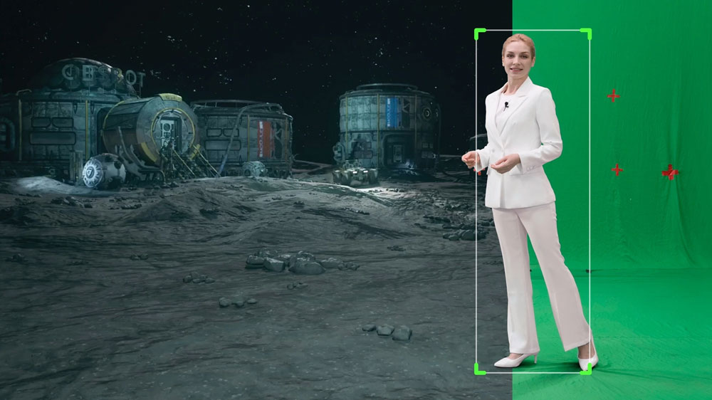 a woman walking in front of a green screen showing a moon base while being tracked by the obsbot ptz camera