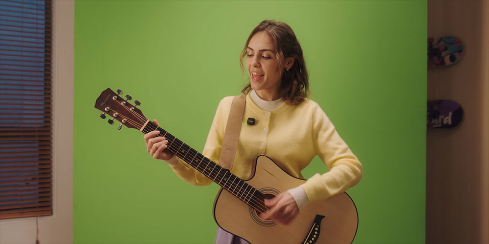 woman playing guitar infront of a green screen