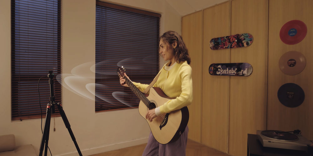 somone using the obsbot tiny on a tripod while playing a guitar
