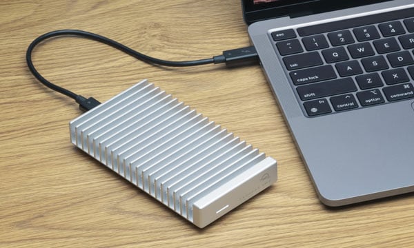 owc ssd drive connected to a laptop on a wooden desk