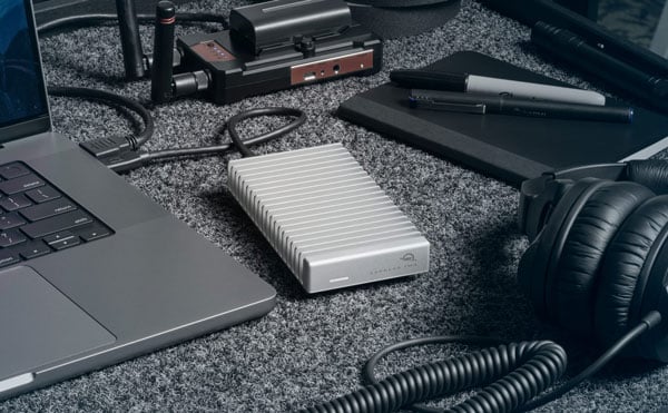 owc nvme ssd connected to a laptop via usb next to a notbook and pair of headphones on a desk