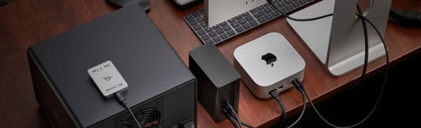 Apple Mac mini desktop setup with the OWC storage enclosure and power adapter on a wooden desk