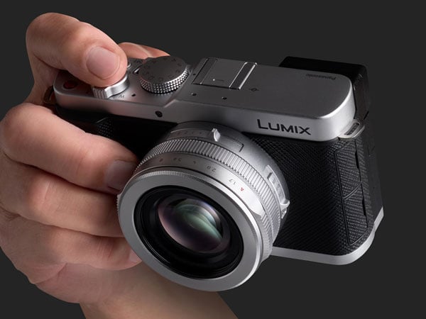 a hand holding the lumix l10 camera on a grey background