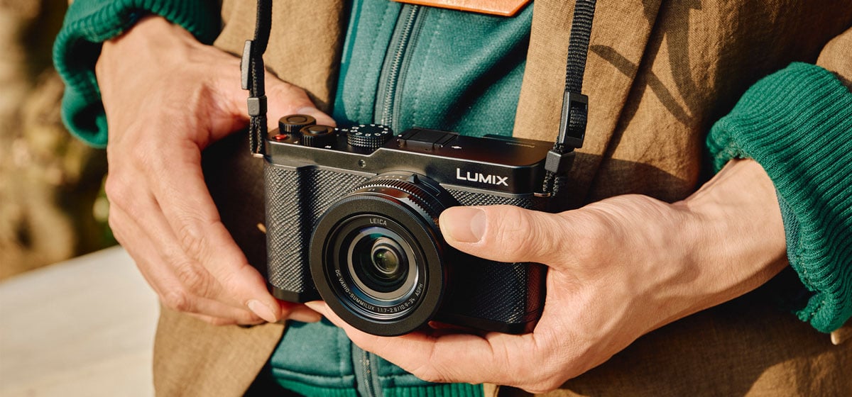 someone holding the panasonic camera while adjusting the lens