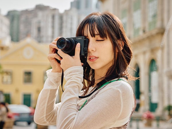a woman taking a photo looking through the view finder while using the lumix l10