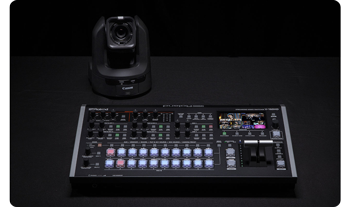 Roland V-160HD panel sat on table with Canon PTZ camera in black room