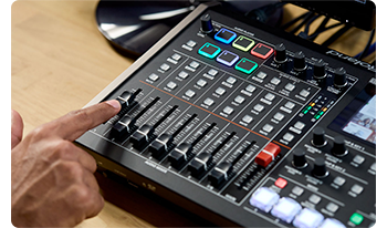person adjust audio control faders on roland VR-6HD