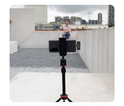 samsung smartphone mounted on a tripod with saramonic wireless receiver filming someone in front of a city