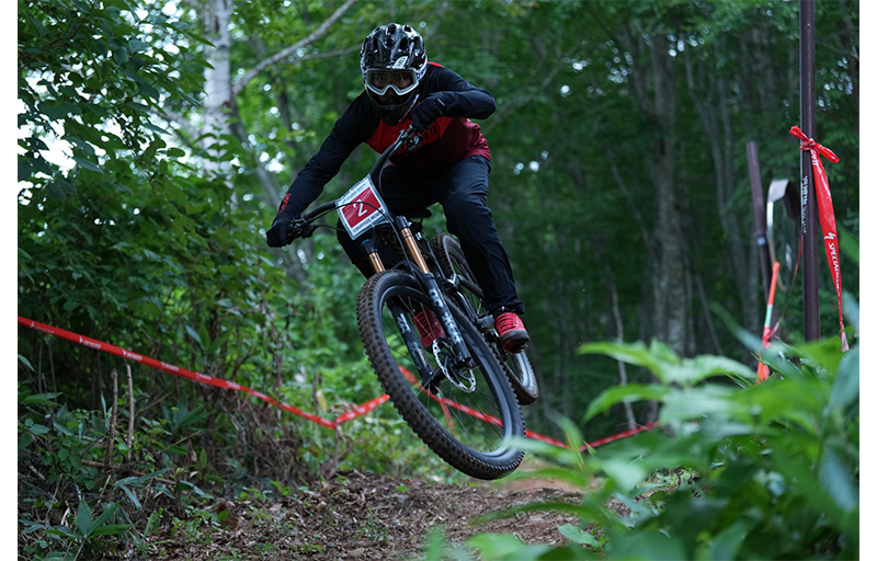 Sony A1 Mirrorless Camera Sample Image of mountain bike racer jumping on track wearing red and black protective gear