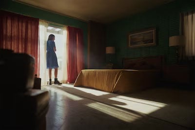 sample image of a woman standing by a sunlit motel room window