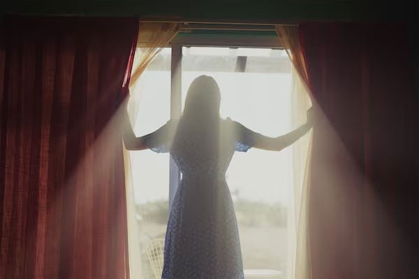 sample image of a woman opening the curtains to a room