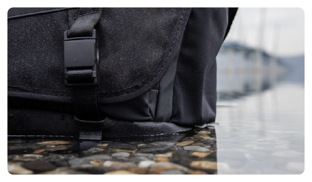 close up of the bottom of the tenba messenger bag in a puddle