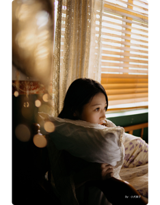 sample photograph of female model sat on couch infront closed blinds with sunlight glowing through