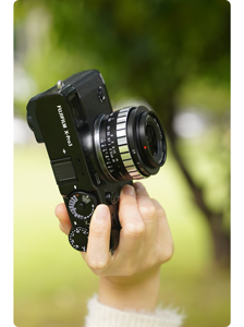 TTArtisan APS-C 23mm F1.4 mounted on Fujifilm XPro3 held in portrait in a grassy field