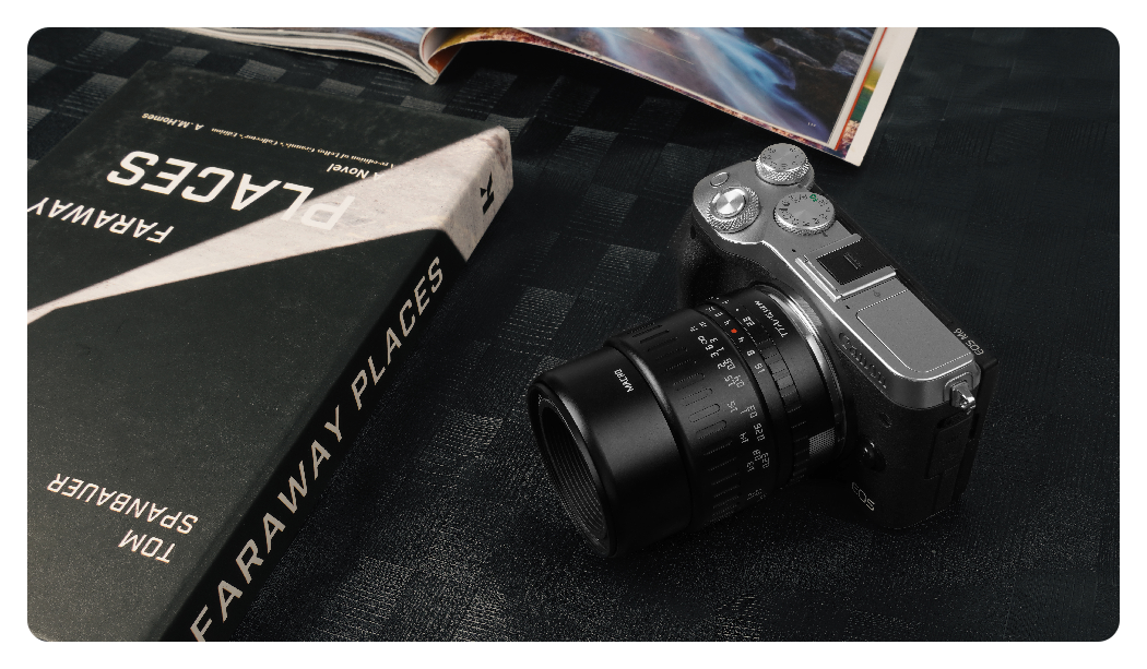 the ttartisan macro lens attached to a camera on a grey background
