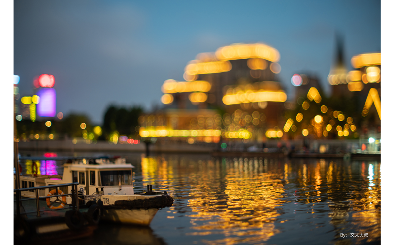 sample photograph of small boat moored at a dock in front of illuminated city at night