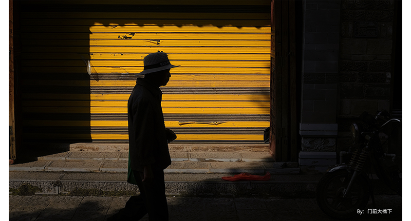 sample photograph of man walking in front of yellow shutter covered storefront