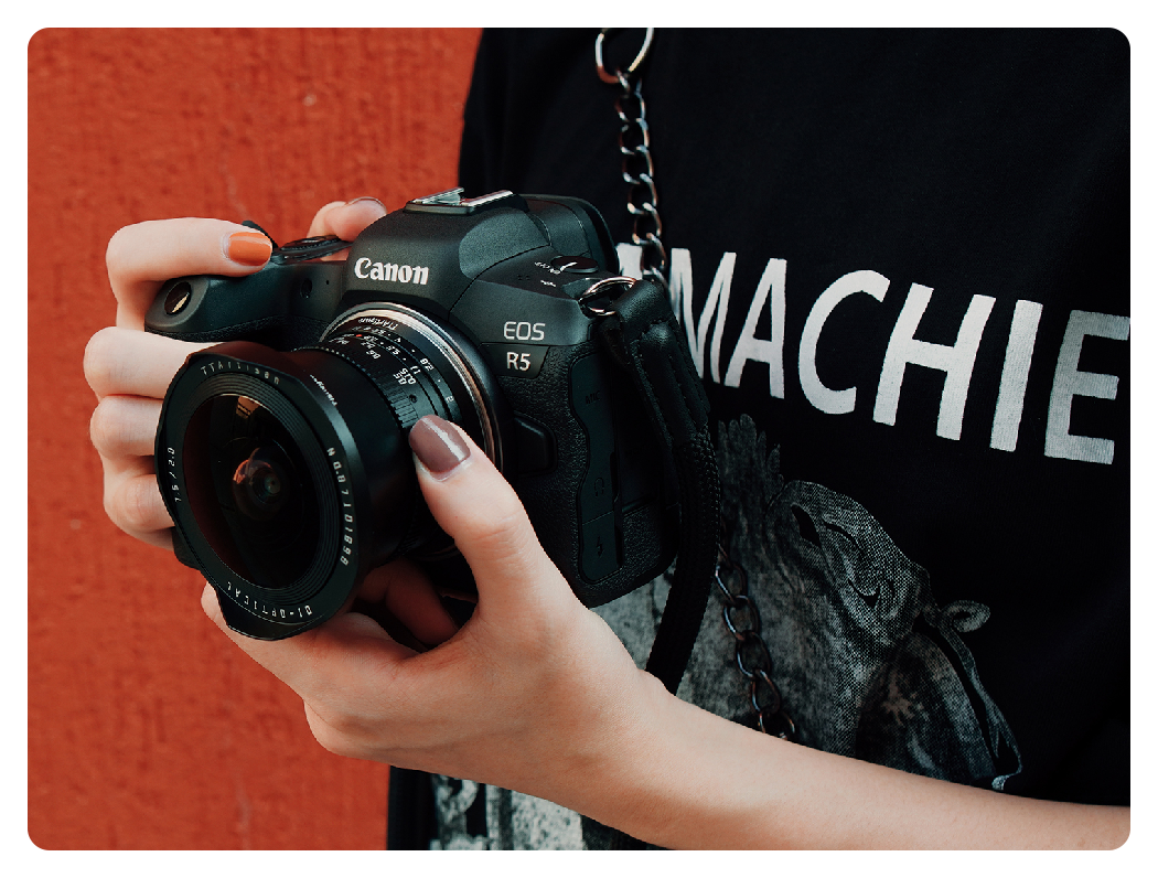 someone holding the ttartisan fisheye lens attached to a camera
