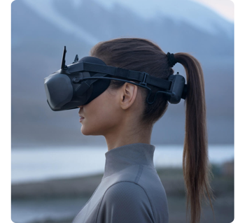 female drone pilot with pony tail wearing DJI Goggles N3 standing infront of mountain lake