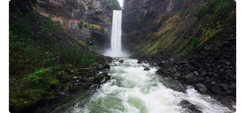DJI Neo drone flying along river towards large waterfall in background
