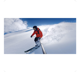 Snowboarder holding selfie stick riding down mountain with wide field of view