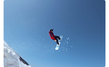 photograph of snowboarder flying through the air infront of clear blue sky