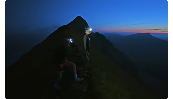 photograph of two female runner standing atop a mountain at night