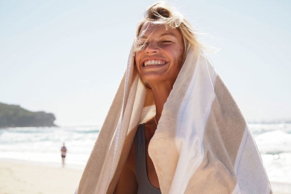 XF16-50mm sample portait photograph of blonde woman smiling on beach wearing towel over head as shade 