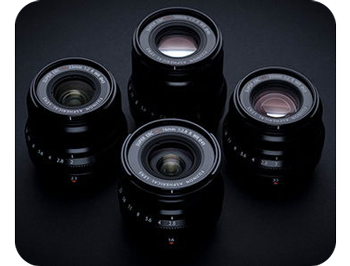 photograph of 4 wide angle fujifilm lenses sat together on black table 