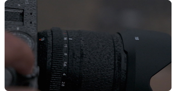 Close up photograph of Fujifilm XF18mm F1.4 R LM WR lens covered in water droplets