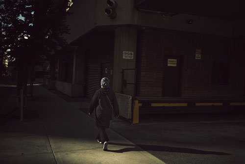 sample street photo of weoman walking along pavement next to large concrete loading dock area