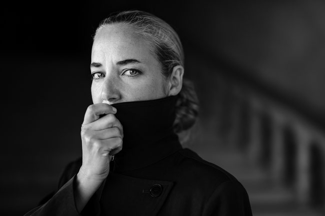 XF50mm black and white Sample image from Knut Koivisto of woman looking to lens wearing tall wool coat covering her face