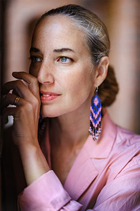 XF50mm F1.0 sample photo from Knut Koivisto of blond woman looking off screen wearing pink suit jacket and long blue patterned earrings
