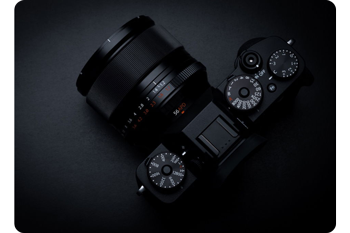photograph of fujifilm X-Pro camera with XF56mm R APD lens on dark table