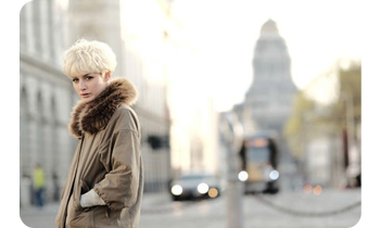 Street portrait of blonde haired woman wearing large fur lined jacket on london street
