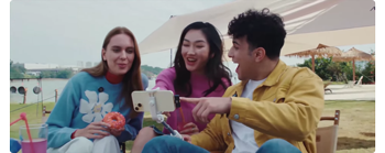 photograph of group sitting with iphone and selfie stick on beach