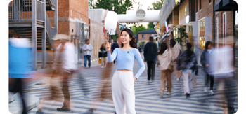 photograph of asian woman wearing blue shirt standing in middle of busy street 