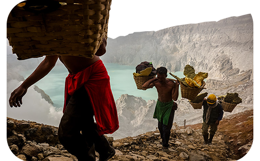 Men carrying mined stone in woven baskets on their shoulders from a quarry