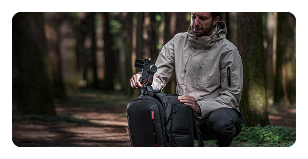 someone pulling a camera attached to a tripod out of the pgytech onemo 2 camera backpack