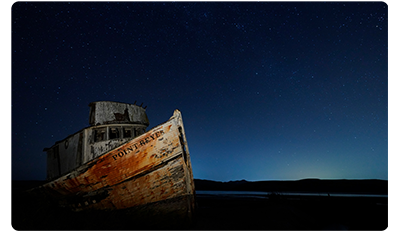 Sony FE 12-24mm F2.8 GM Lens sample image of old beached fishing boat lit by camera flash against the clear night sky