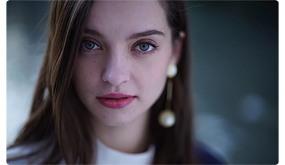 Sony FE 50mm F1.2 G Master Lens sample portrait of brown haired woman with sharp blue eyes and pink lipstick wearing pearl earings 